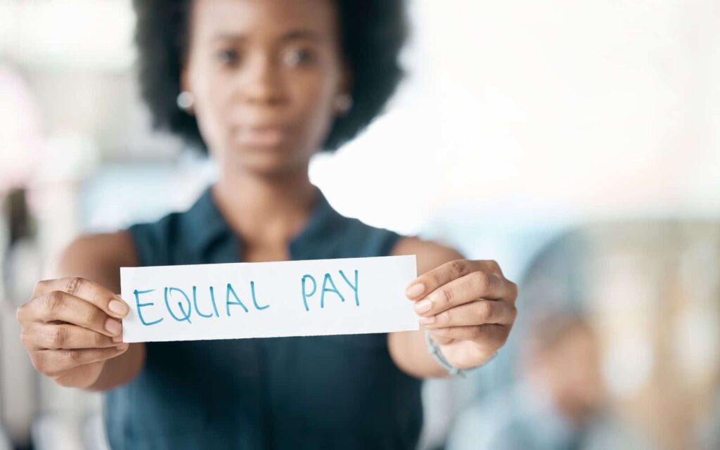 Frau hält Schild mit der Aufschrift Equal Pay als Statement für Lohngerechtigkeit