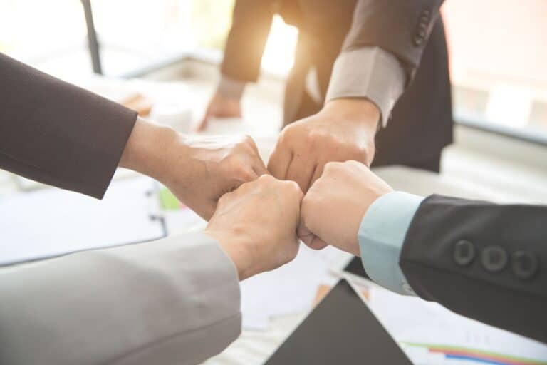 Mehrere Personen im Büro machen eine Fist-Bump-Teamgeste