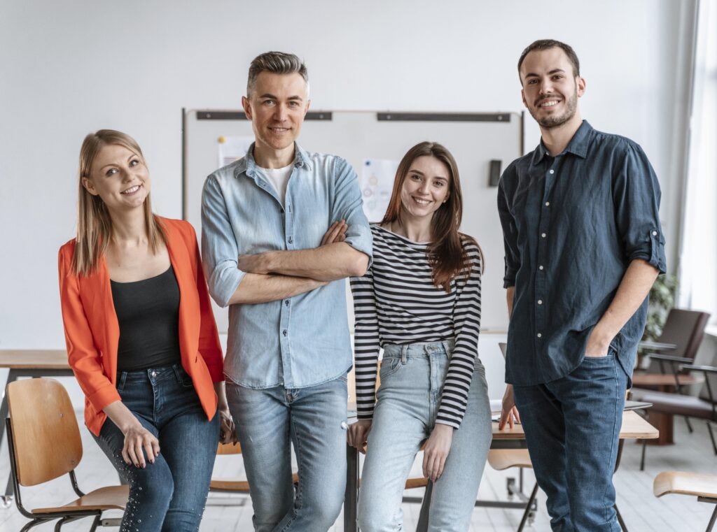 Gruppe junger Mitarbeitender posiert gemeinsam im Büro