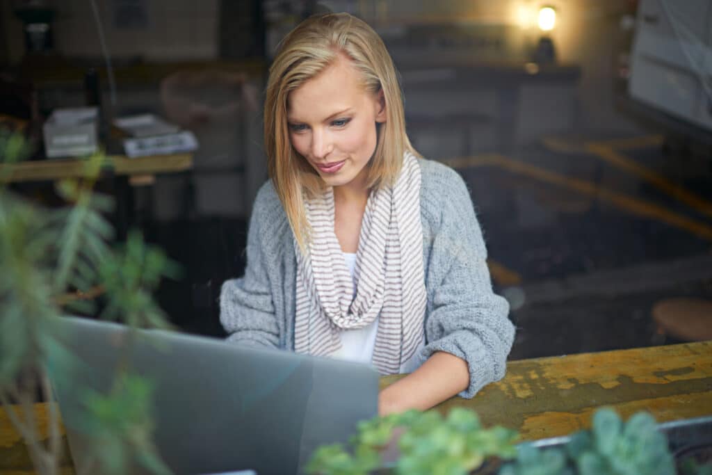 Frau arbeitet im Café an einem Laptop – Nachhaltigkeit in der IT