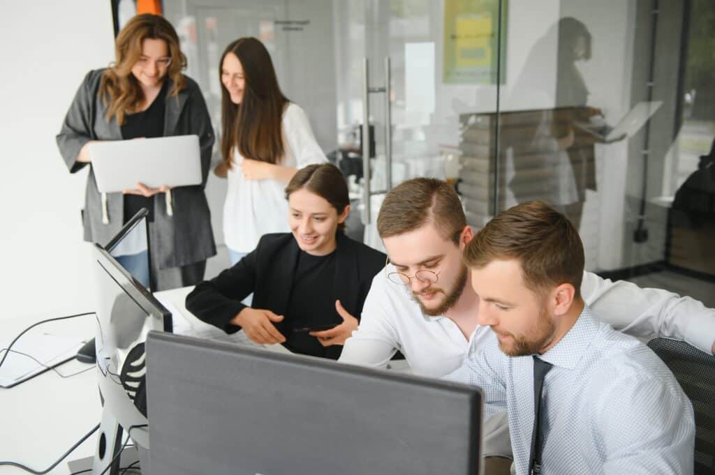 Gruppe junger Mitarbeiter arbeitet gemeinsam vor einem Computer im Büro