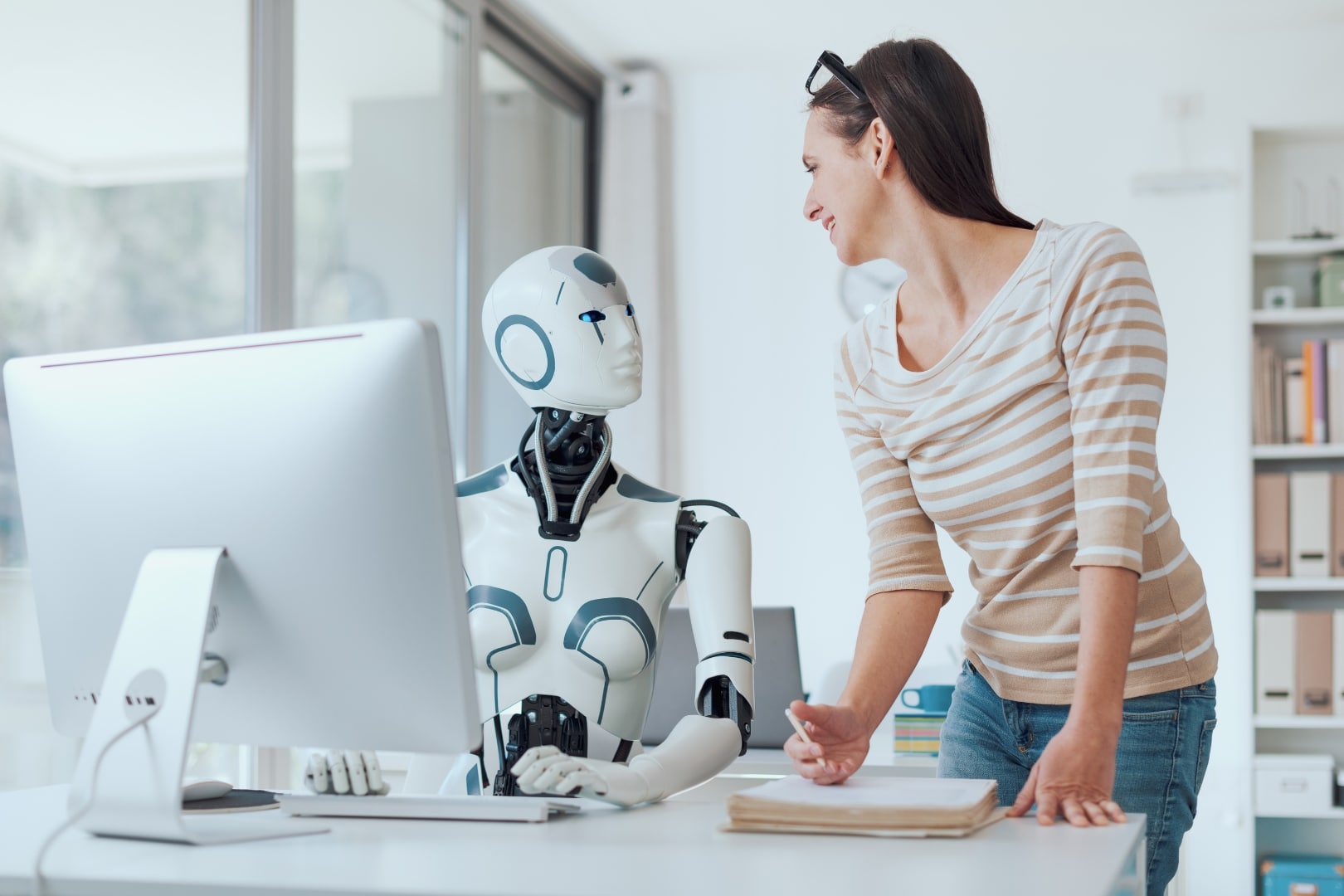 KI im Recruiting: Frau interagiert mit humanoidem Roboter im modernen Büro