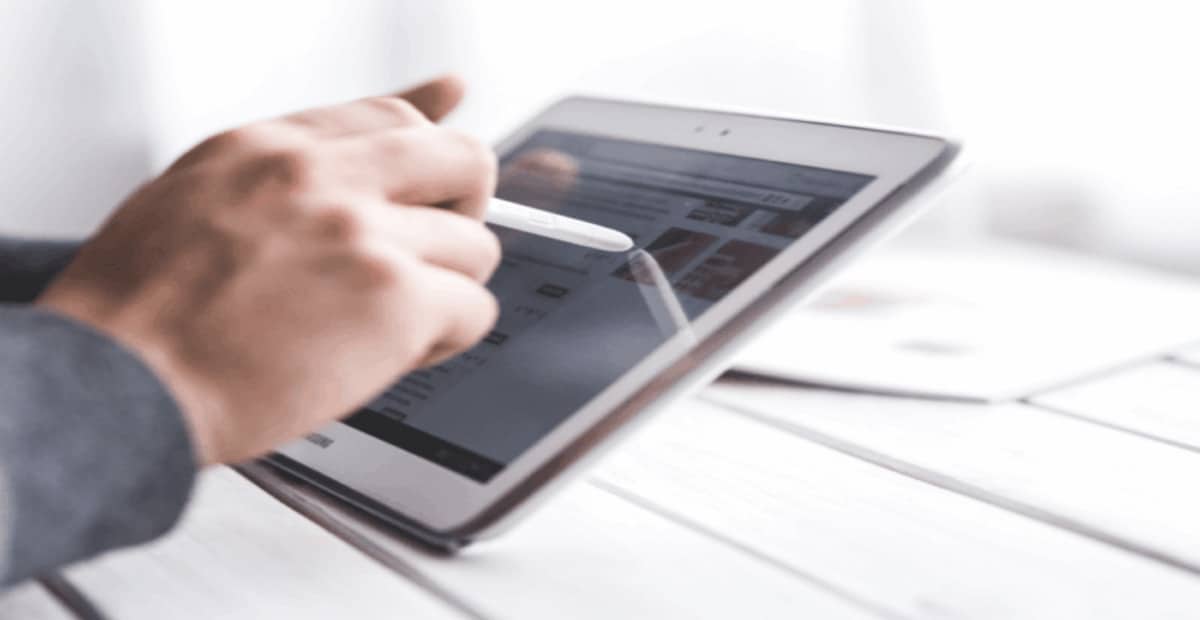 Hand, die mit einem digitalen Stift auf ein Tablet tippt